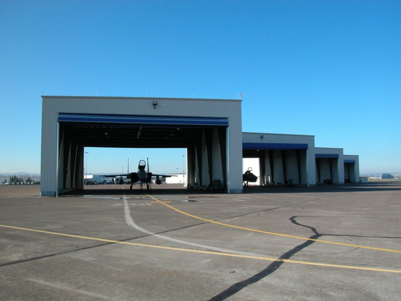 Outdoor shot of fighter jets inside individual hangars.